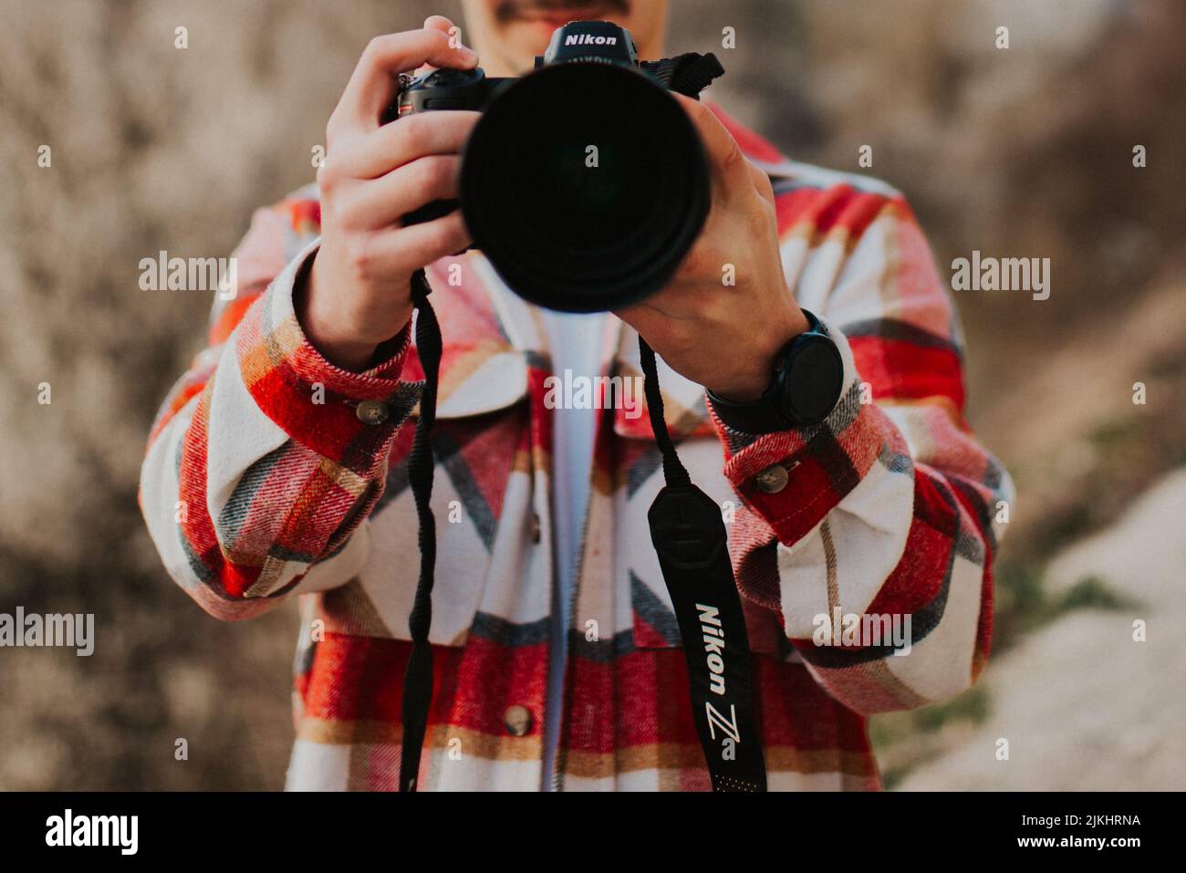 A male holding a Nikon Z6 camera against a blurred background in Cazin, Bosnia and Herzegovina Stock Photo