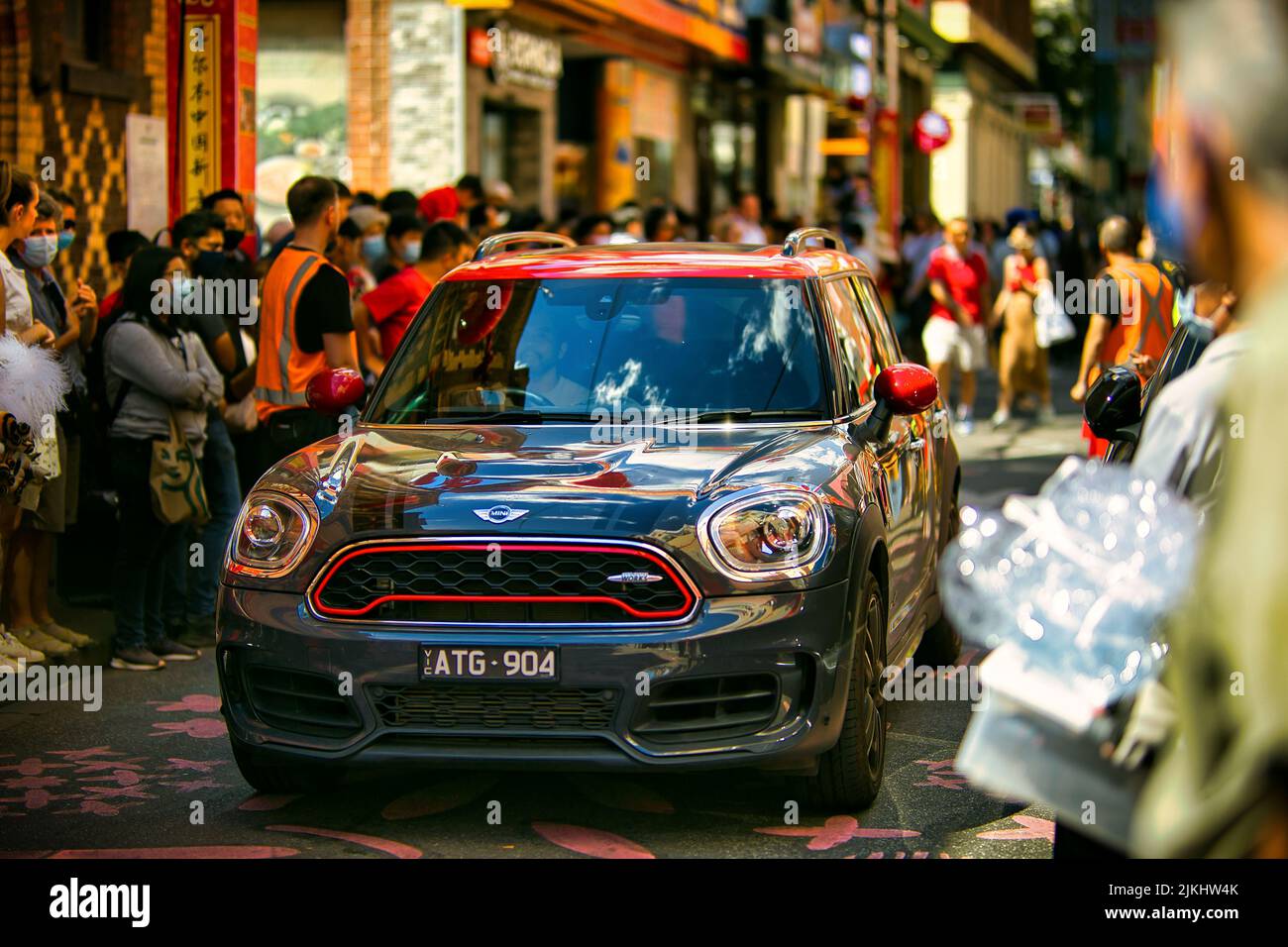a Picture of a mini cooper driving along the street of Chinatown in