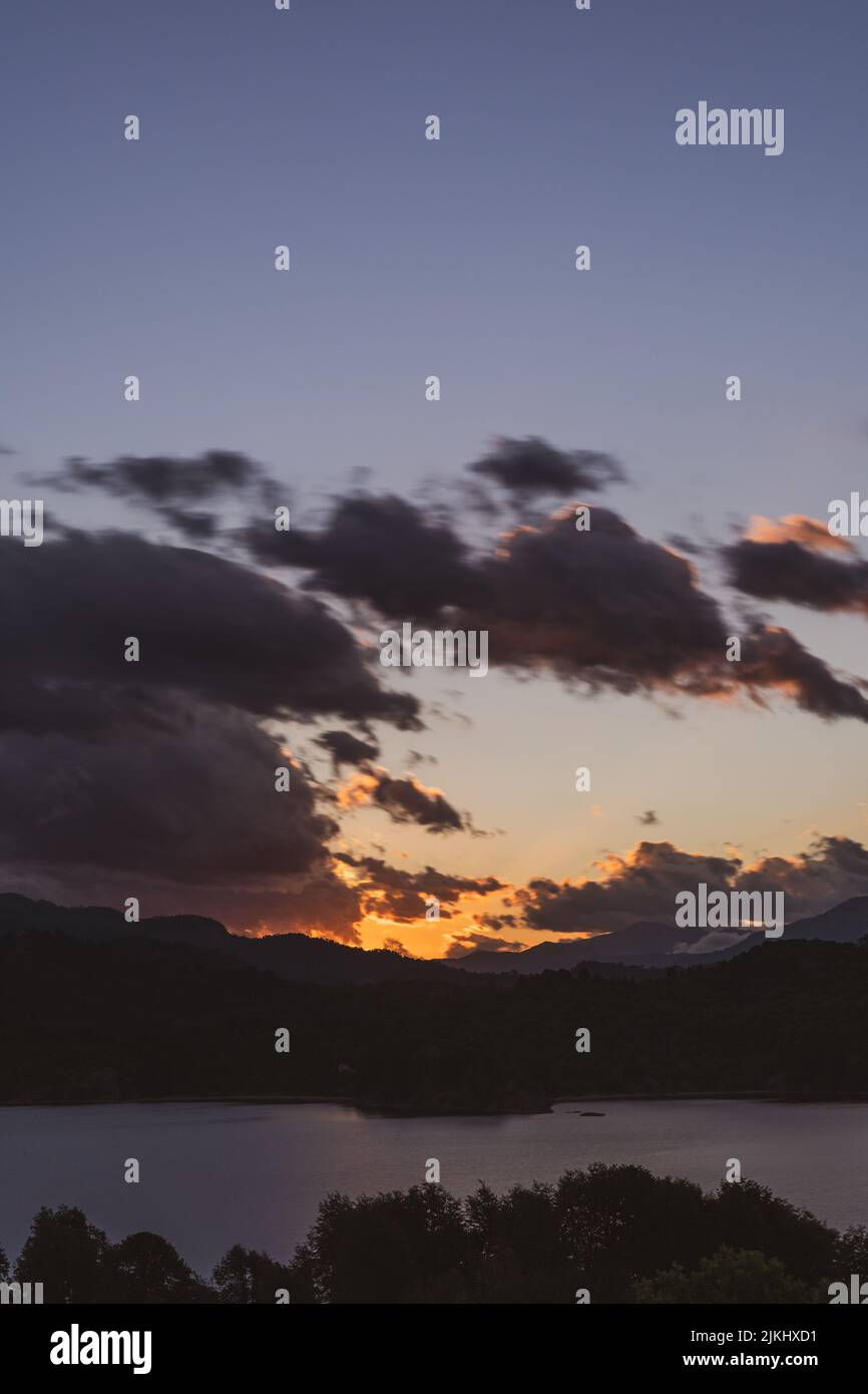 A vertical shot of a calm lake surrounded by trees at sunset Stock ...