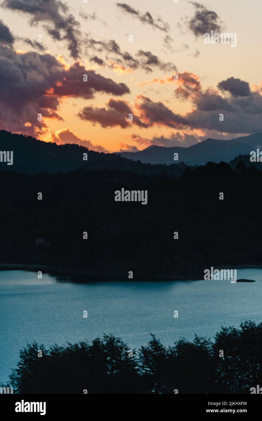 A vertical shot of a calm lake surrounded by trees at sunset Stock ...
