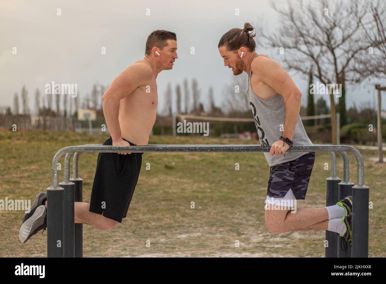 A photo of two men doing a sports session together, face to face on the cross-bar in balance Stock Photo