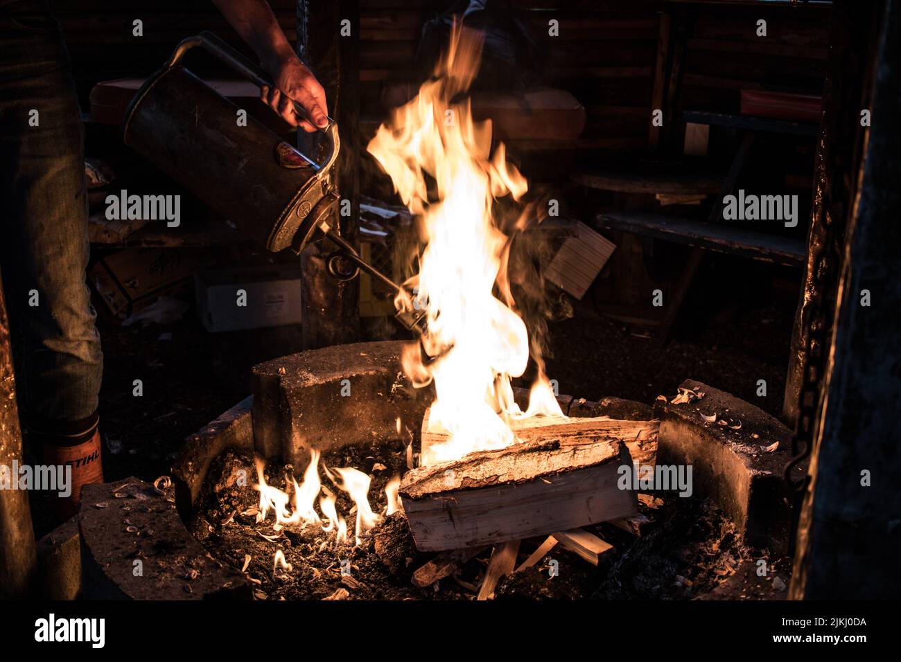 A person's hand holding a drip torch lighting a campfire Stock Photo
