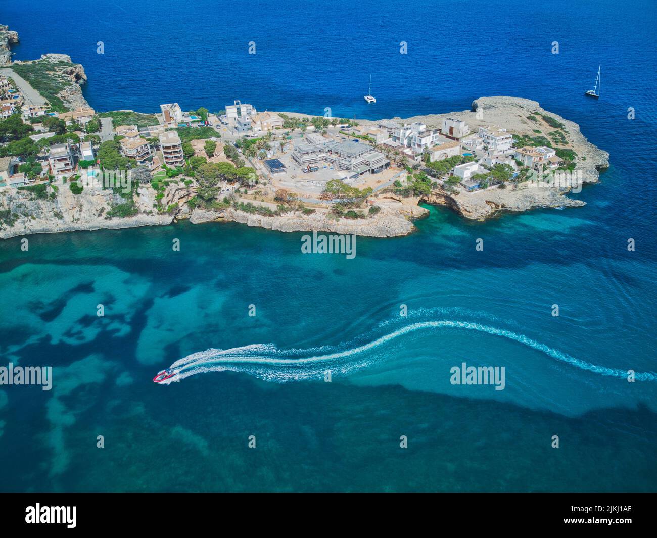 Spain, Balearic islands, Mallorca, district of Manacor, Portocristo. A motorboat enters the port leaving a trail on the sea Stock Photo