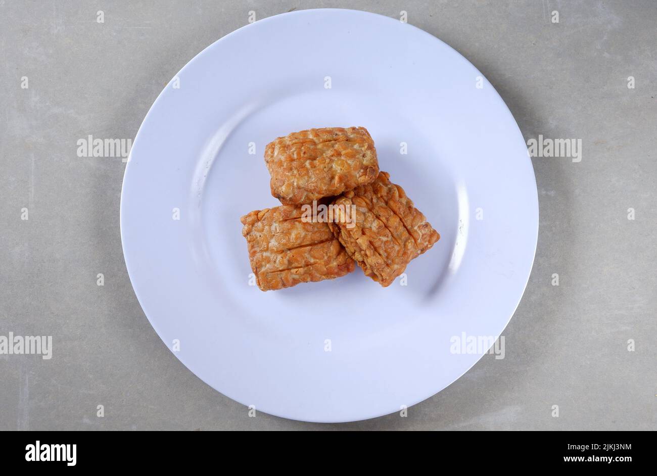 Fried tempeh on a white plate ready to eat, Indonesian food Stock Photo Alamy