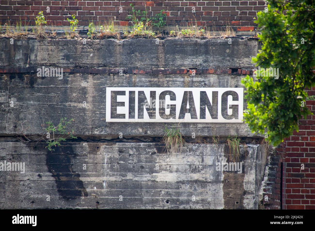A closeup shot of a bunker with a large sign saying entrance in German Stock Photo