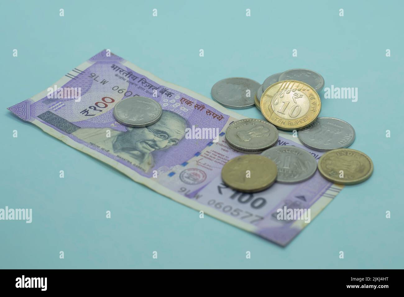 The Indian currency - the 100 rupee note with Indian coins. 1, 5, 10 rupees coins on the blue background Stock Photo