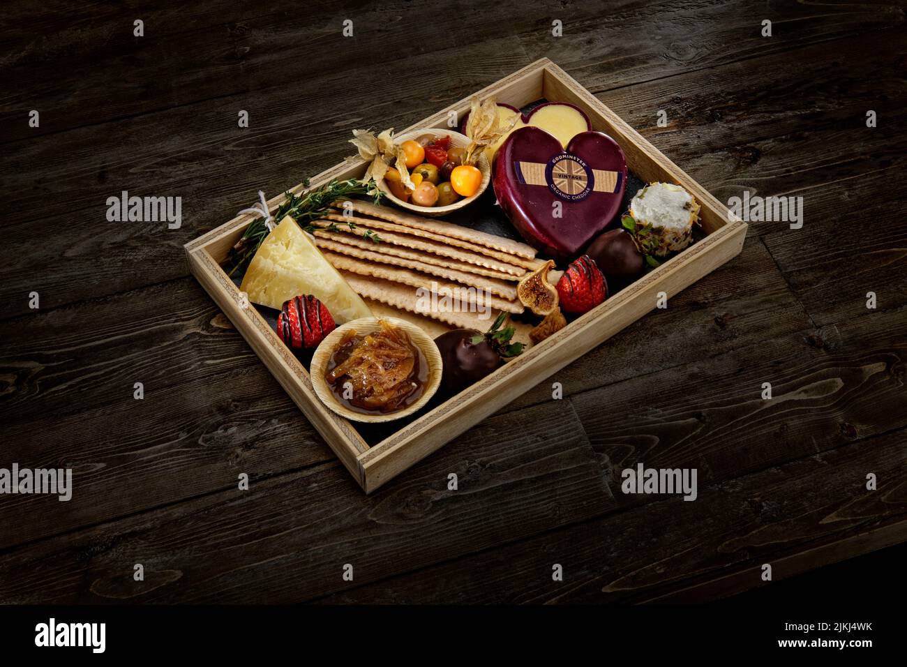 A closeup of a delicious Charcuterie board with crackers, cheeses and cured meats on a wooden platter Stock Photo