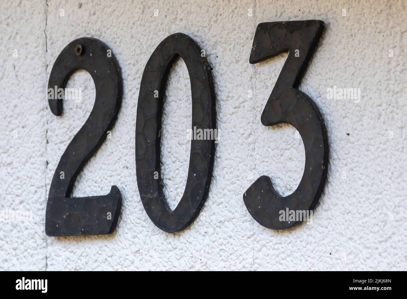 A closeup of house number 203 on white concrete wall Stock Photo