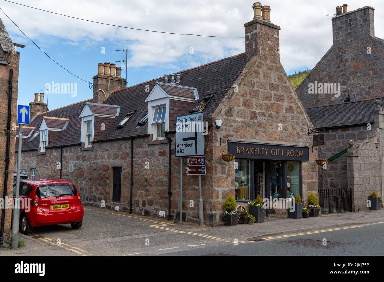 The high street shops of the town of Ballater on a partly cloudy day ...