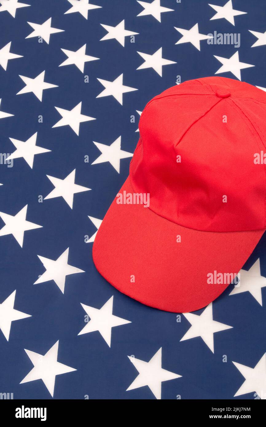 Red MAGA-type hat with blank front area on US Stars and Stripes flag. For Republicans 2024 Presidential election, American elections, US Red Wave. Stock Photo