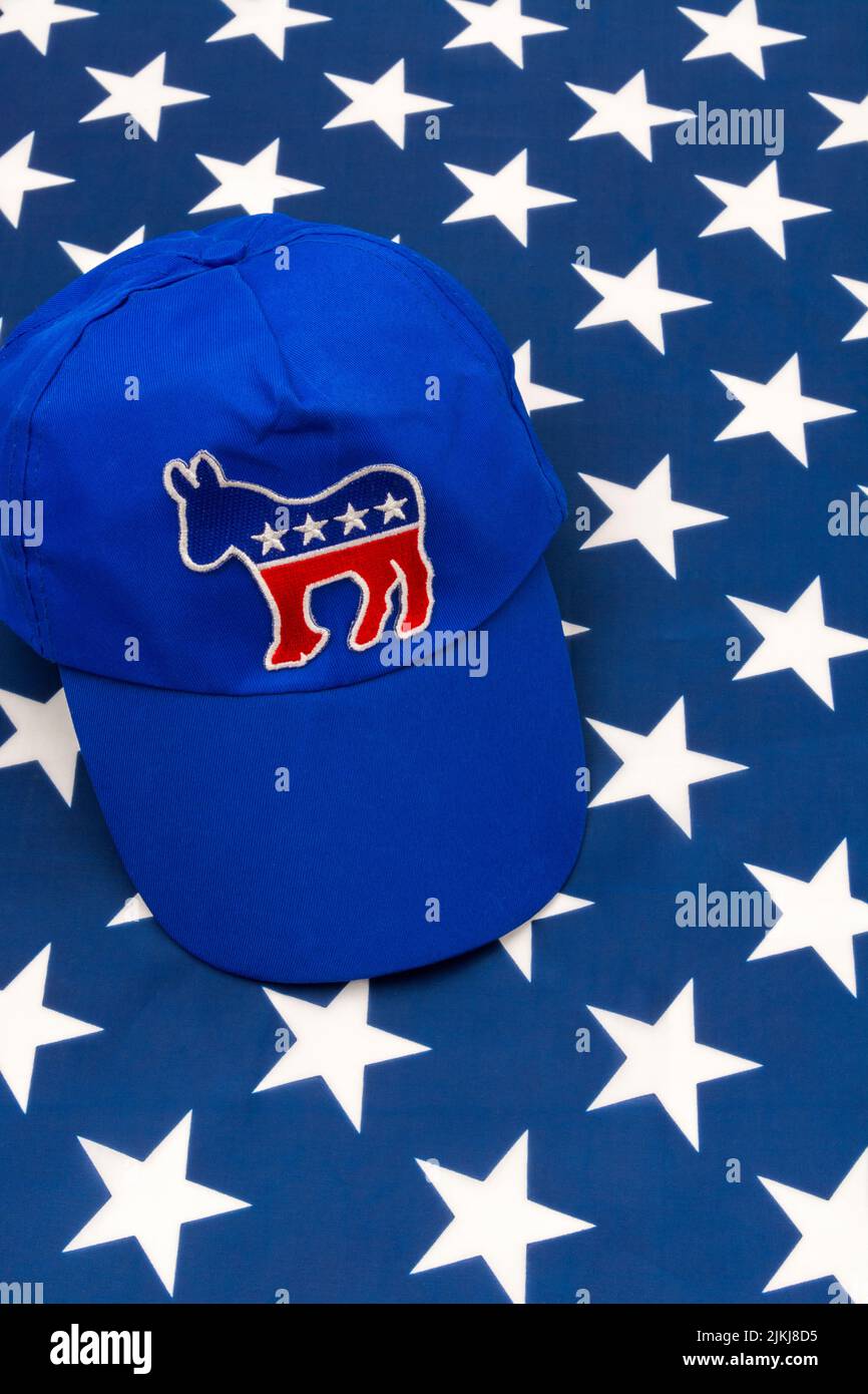 Blue DNC cap with Dem donkey badge & US Stars and Stripes flag. For 2024 US Presidential election & Republican Red Wave wipe-out of Democrats. Stock Photo