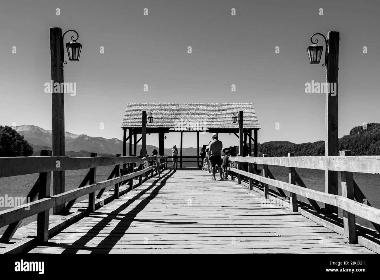 A grayscale shot of tourists on a wooden coast platform during summertime Stock Photo