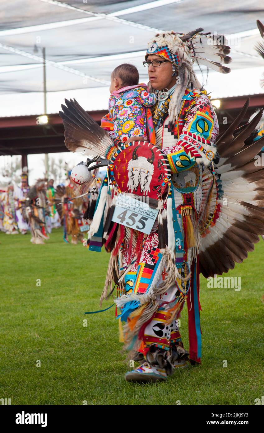 Pow Wow dancer holds baby while dancing at the Shoshone Bannock Pow Wow