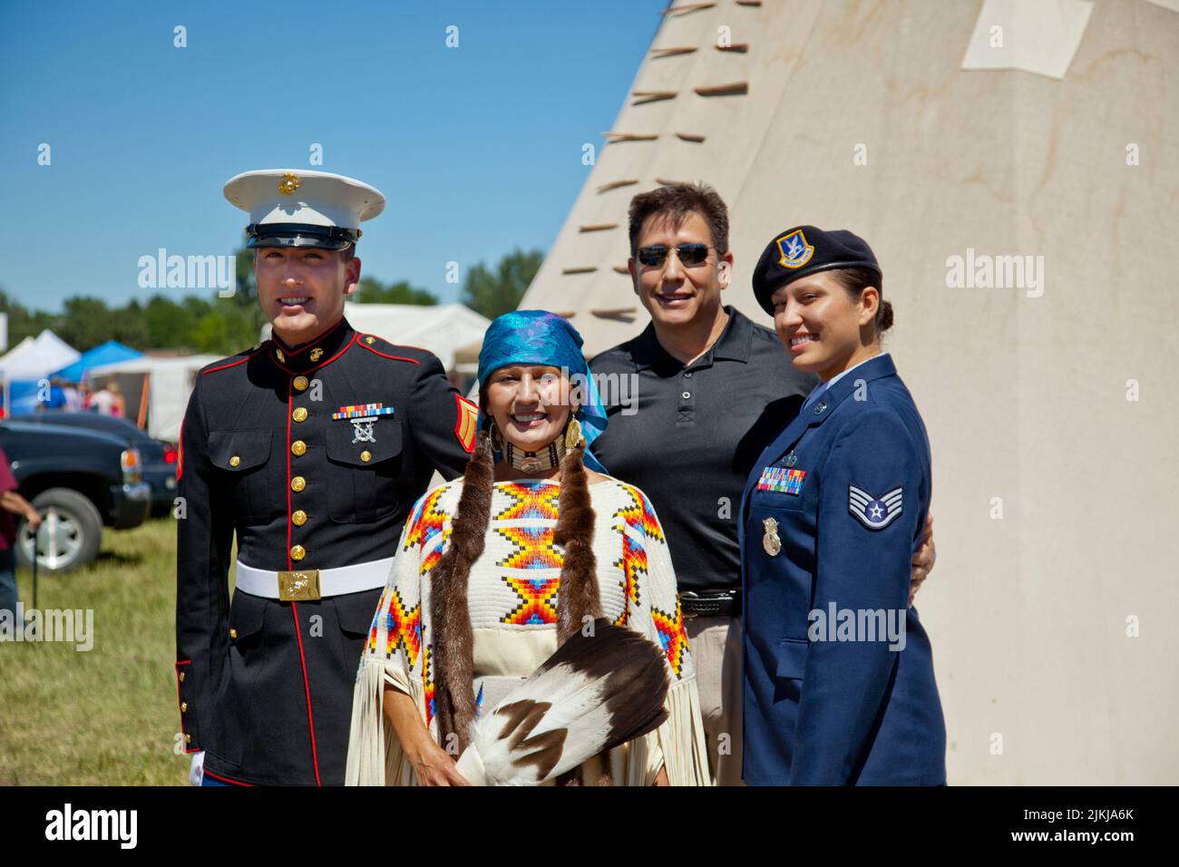 Military family in uniforms and traditional outfit stand in front of a