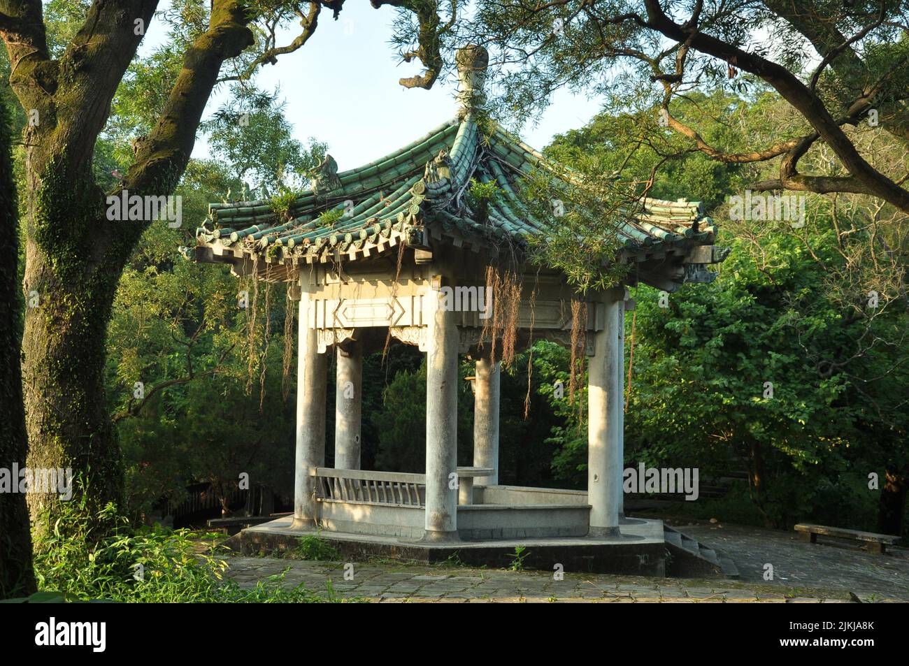 A scenic view of a Chinese pavilion with columns and a green rooftop surrounded by greenery in Taipei, Taiwan Stock Photo