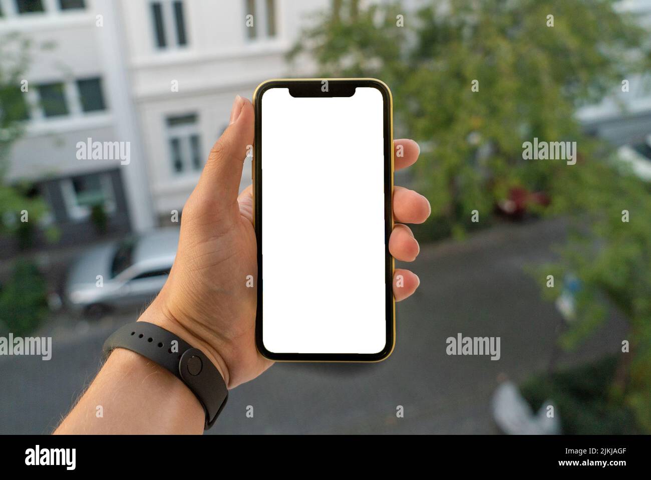 A man hand holding a smartphone similar to an iPhone X with a blank copy space outdoors Stock Photo