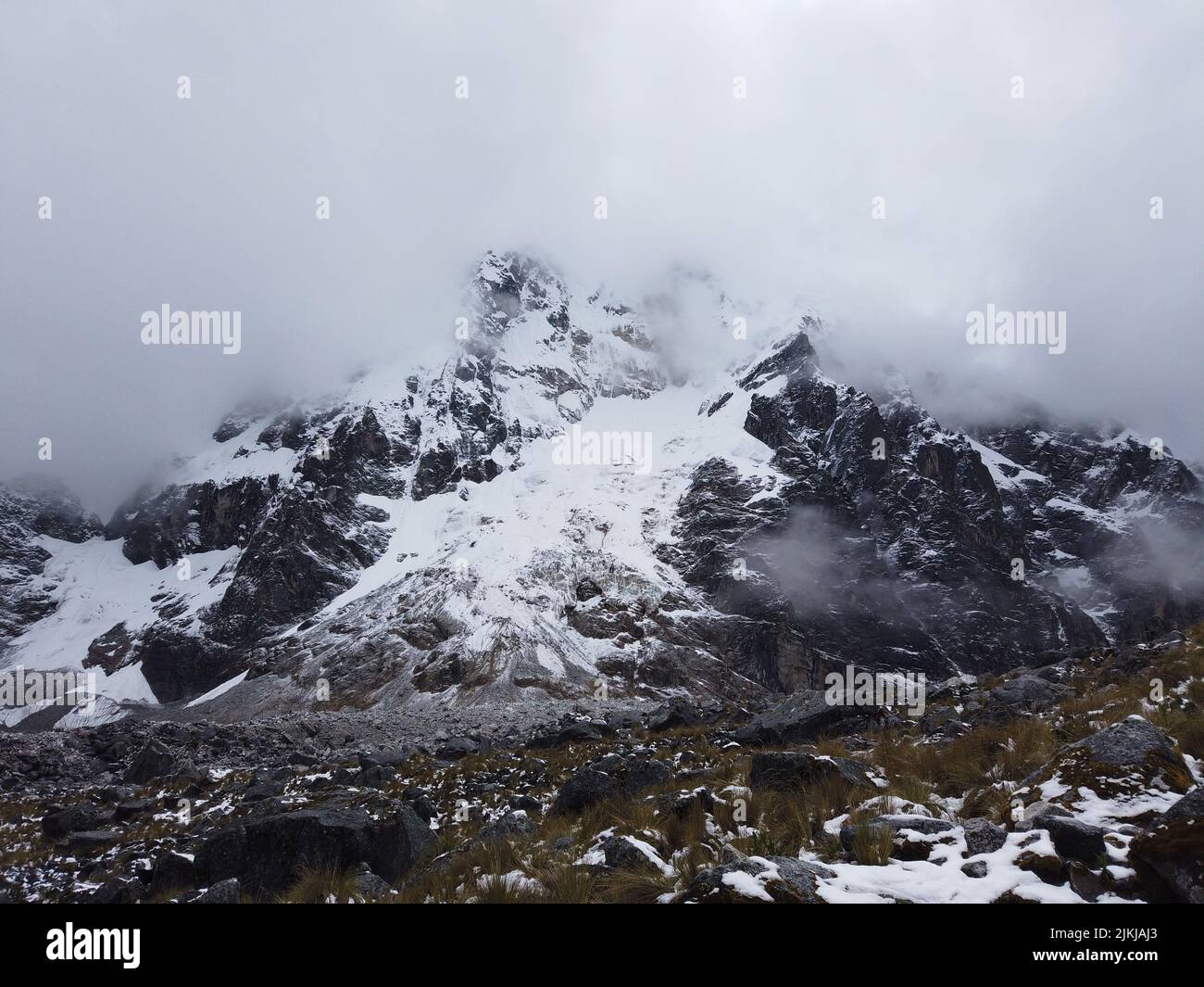 A scenic view of a rocky mountain covered with snow under a cloudy sky Stock Photo