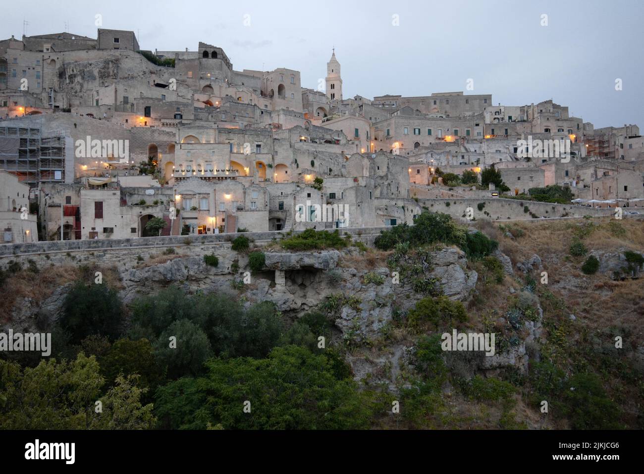 A scenic view of Sassi of Matera cave settlements on a green hill in Italy at sunset Stock Photo