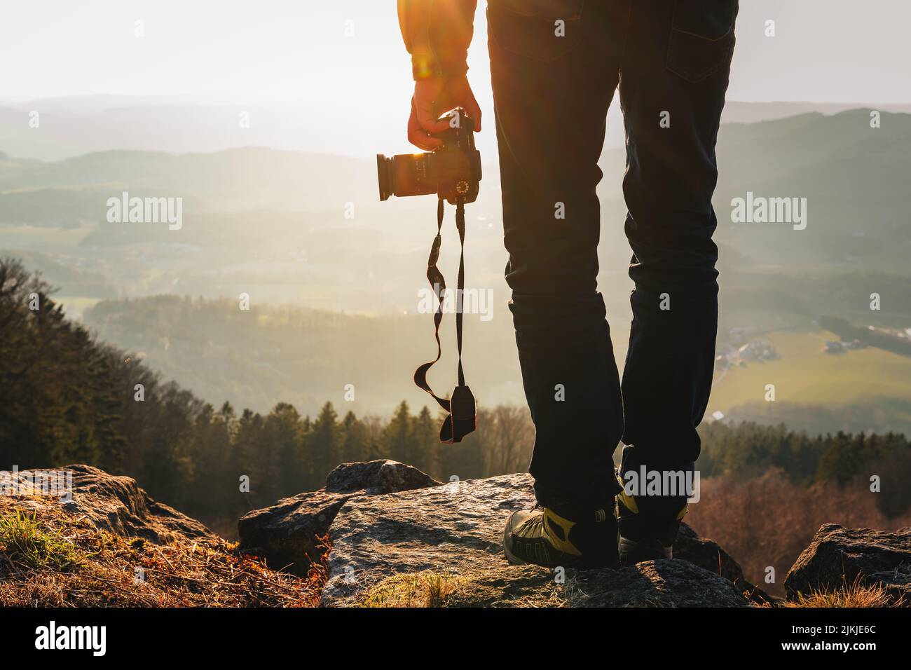 A Photographer with camera in the Bavarian Forest in sunset taking photos of landscape and mountains Stock Photo