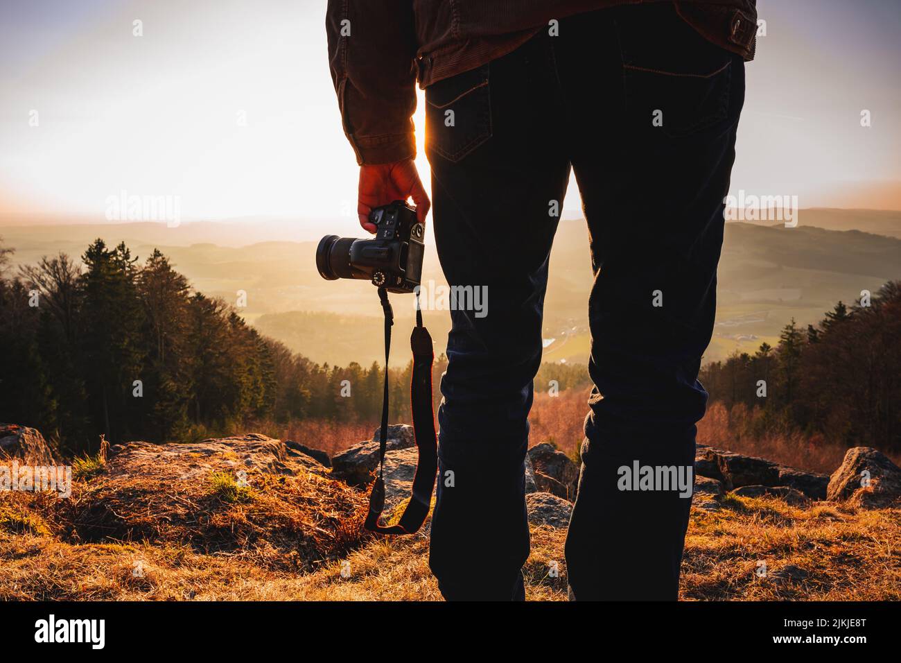A photographer with a camera at sunset taking photos of a landscape in Bavaria Stock Photo