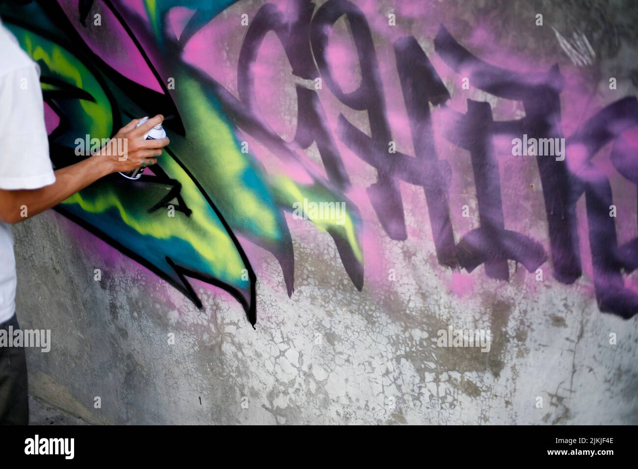 Artist hand drawing graffiti with the aerosole spray paint on the wall