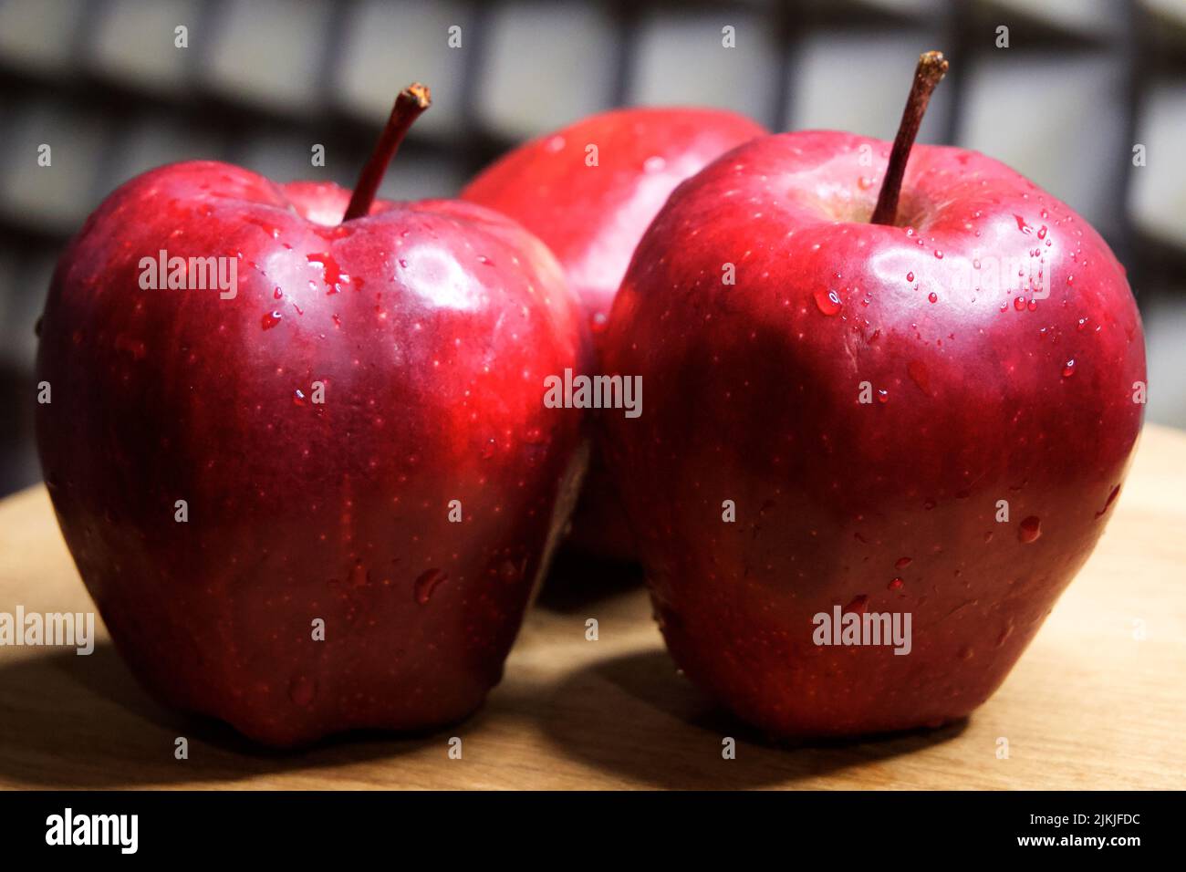 Three large red apples of the Red Chief variety. Water droplets on fruit. Stock Photo