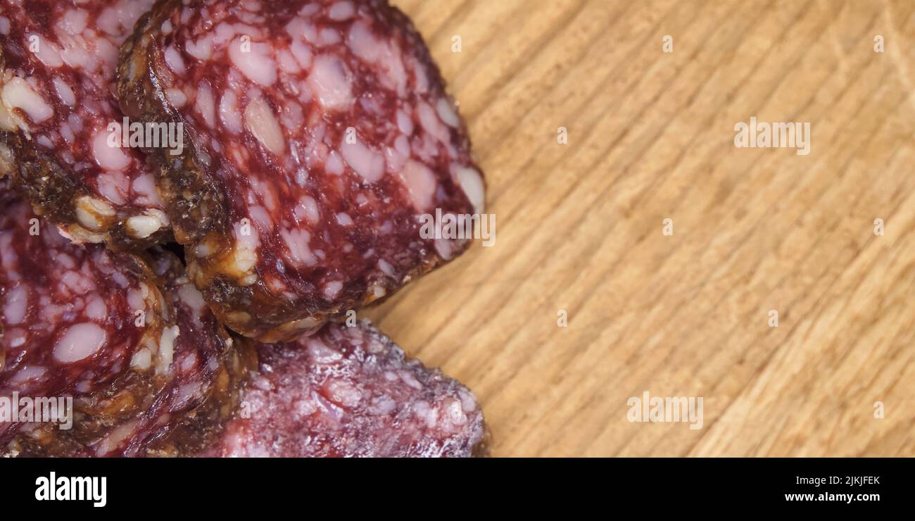 Pieces of delicious smoked sausage on a wooden cutting board, a close-up shot, copy space. Stock Photo