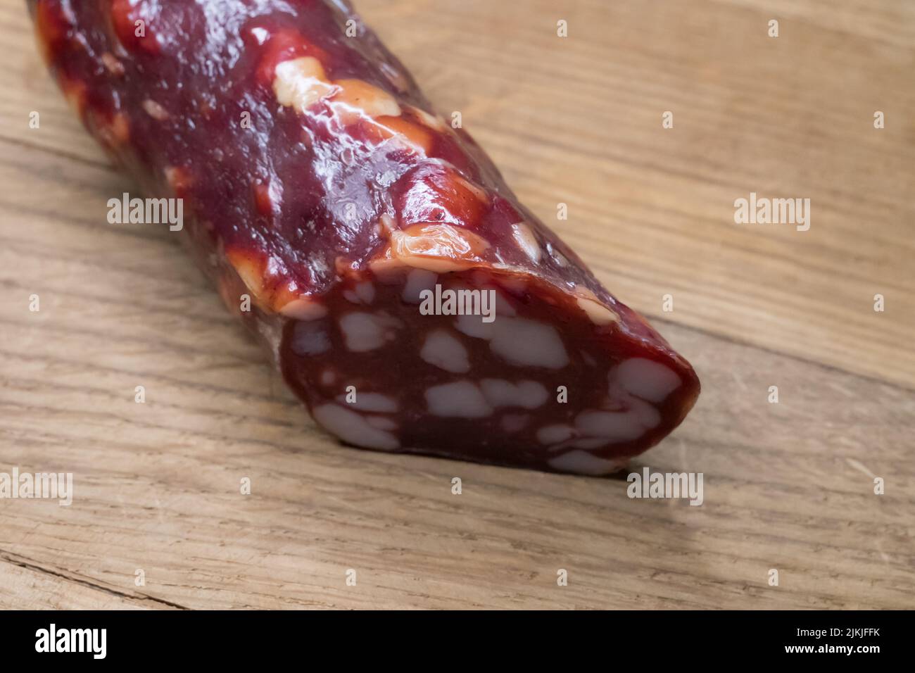 Smoked sausage on a wooden cutting board, food close-up shot. Sausage with a lot of fat. Delicacy dried sausage for food illustration. Tasty sausage o Stock Photo