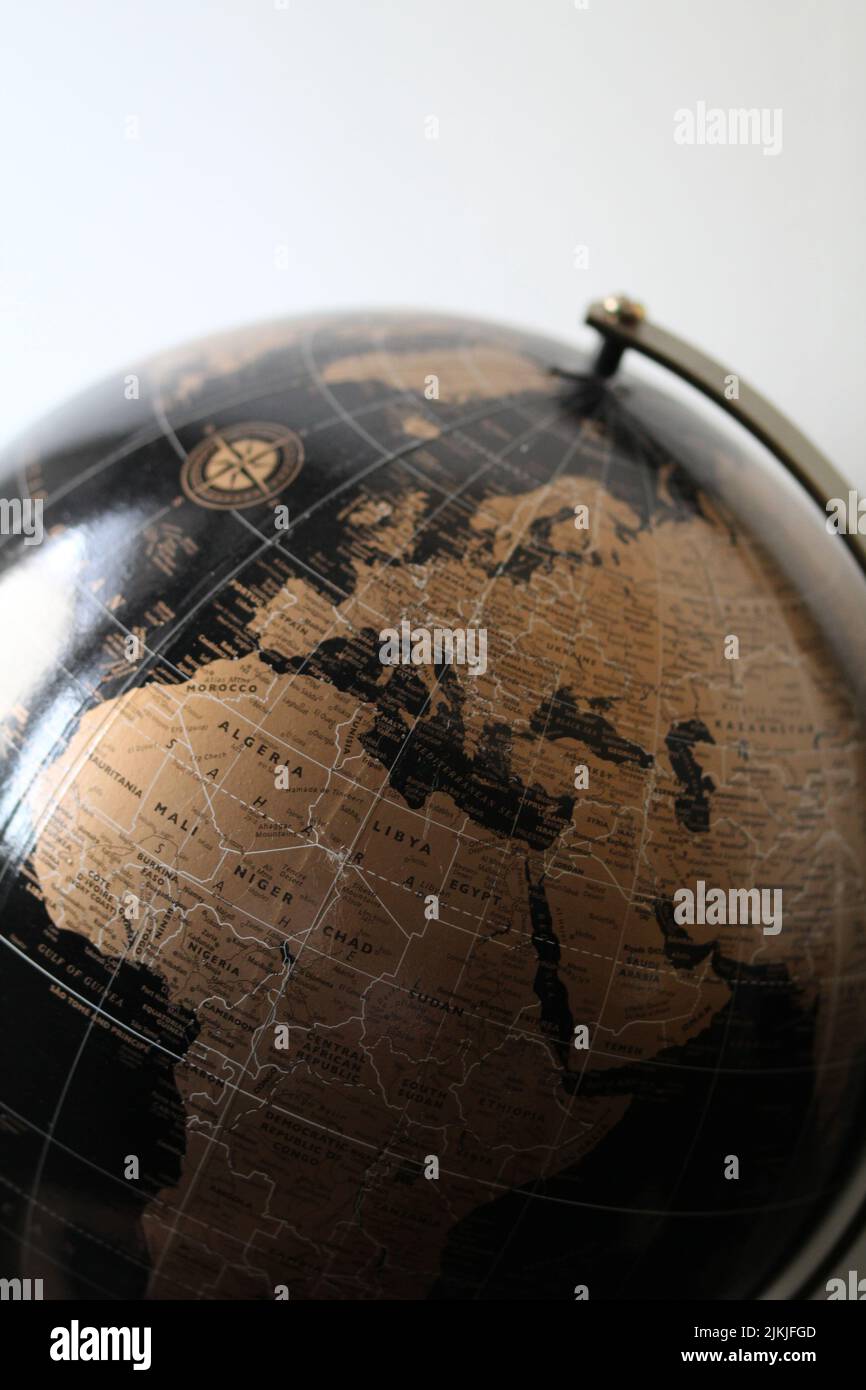 A vertical shot of a black and gold world globe isolated on a blurred background Stock Photo