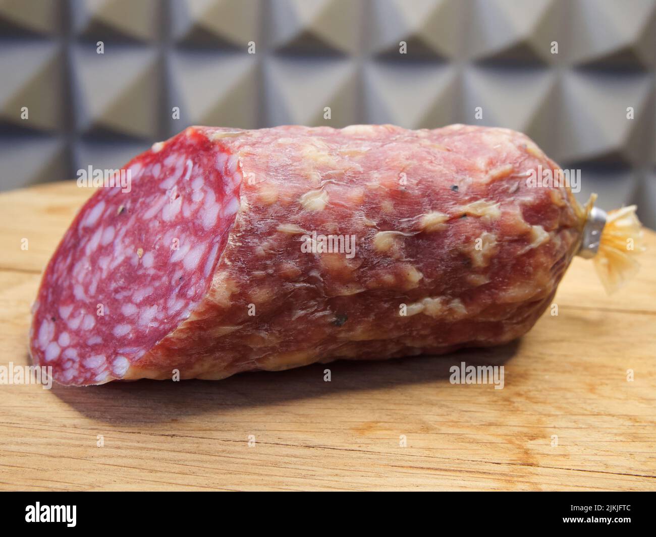 A large piece of smoked sausage on a wooden cutting board. Stock Photo