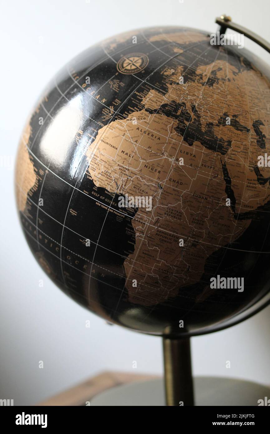 A vertical shot of a black and gold world globe isolated on a blurred background Stock Photo