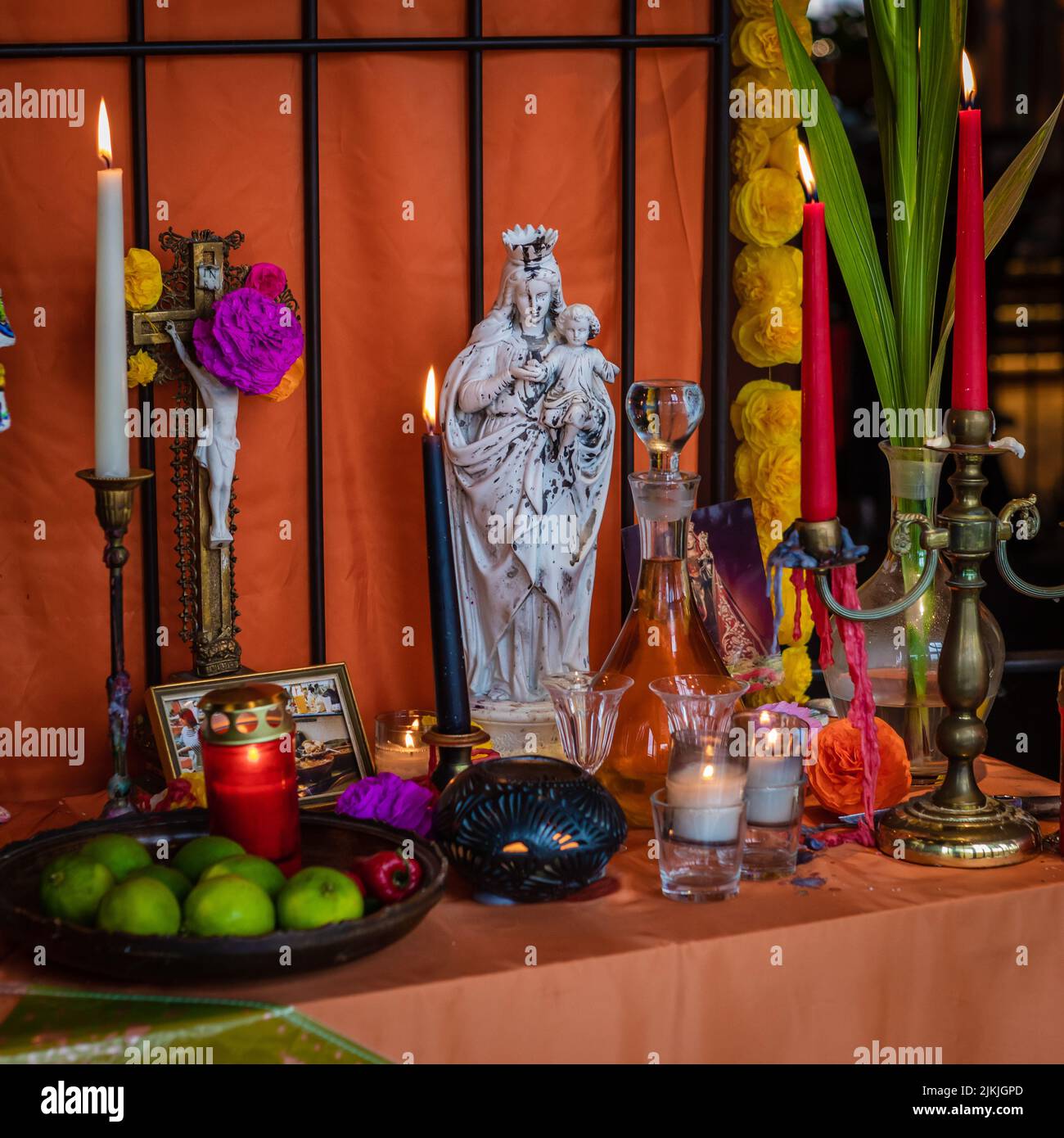 A setup of Dia De Los Muertos decor with candles and a statue of Saint Mary Stock Photo