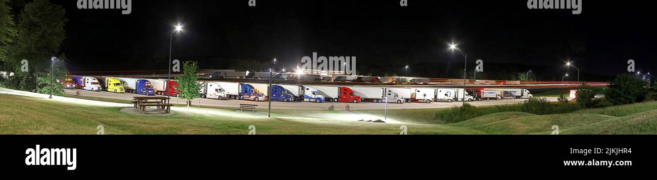 Trucks in rest area at night. Truck stop wayside, parked. Wide view with copy space and lighted foreground. Wide panorama black background Stock Photo