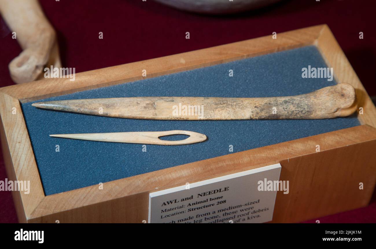 Sharp bone needle with carved eye hole used for sewing and an awl used