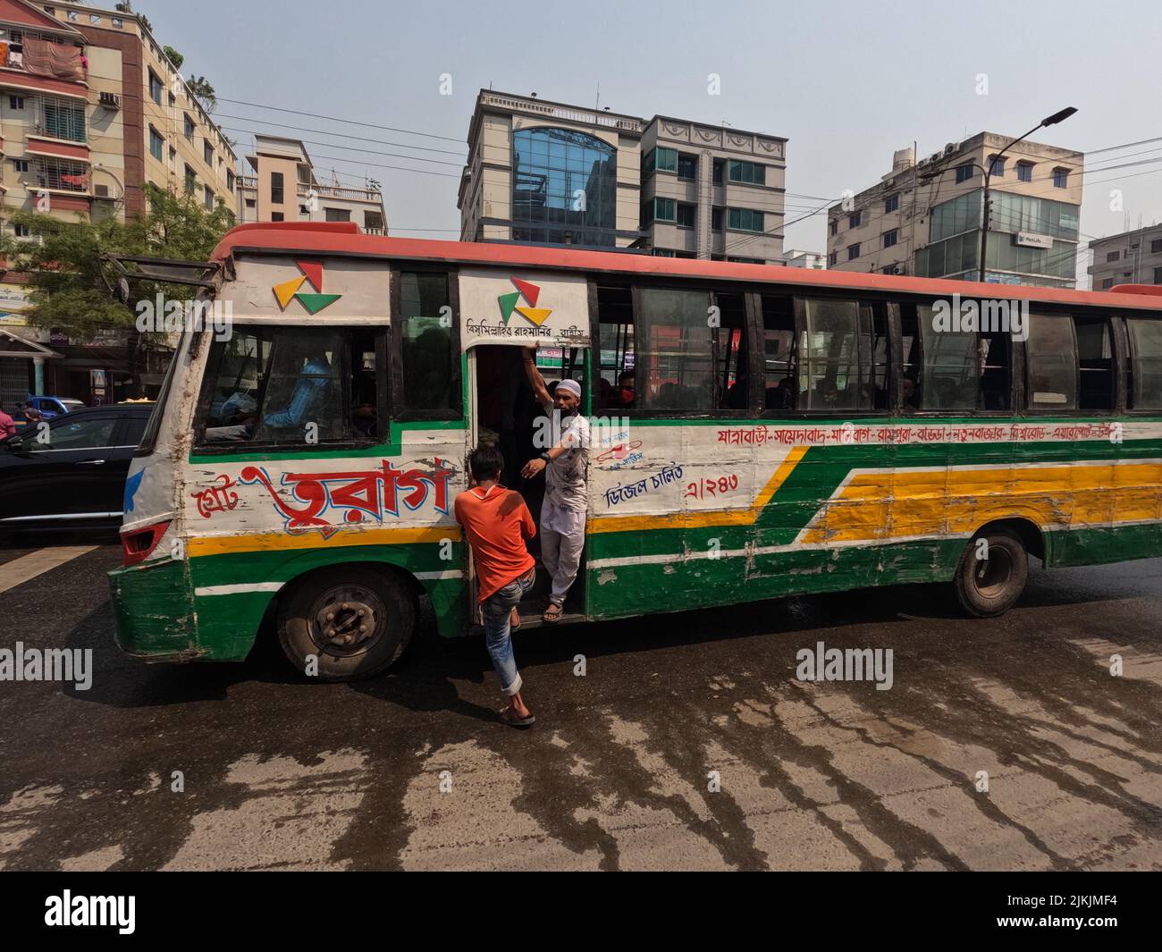 A beautiful shot of a male trying to enter a colorful transport bus in the street in Dhaka, Bangladesh Stock Photo
