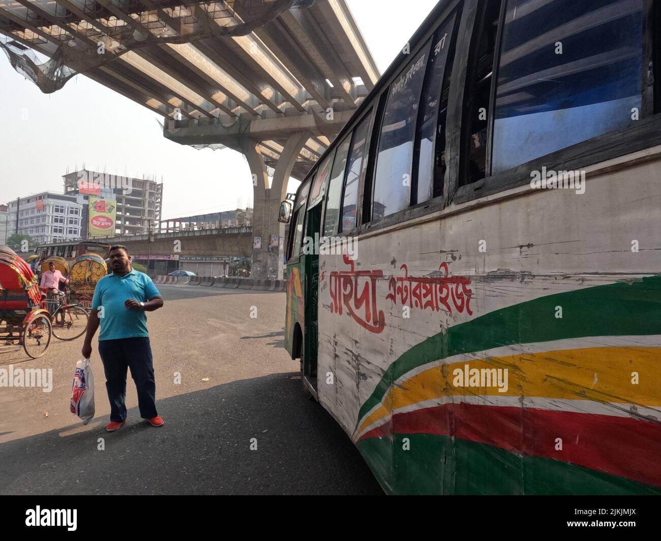 A beautiful shot of a male next to a big colorful transport bus in Dhaka, Bangladesh Stock Photo