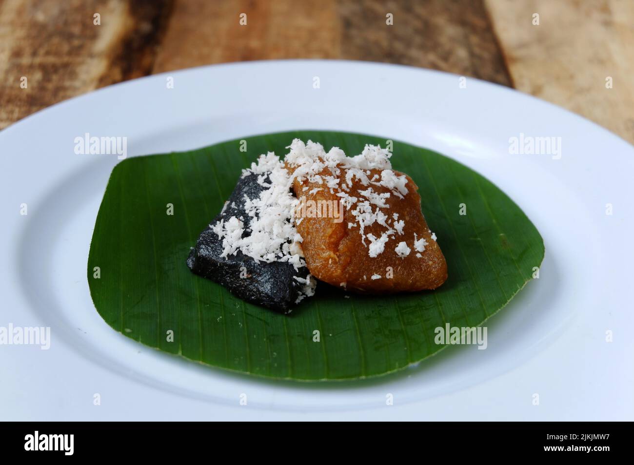 Getuk or food from cassava and coconut on a plate and banana leaf with wooden table, traditional food from Indonesian Java Stock Photo