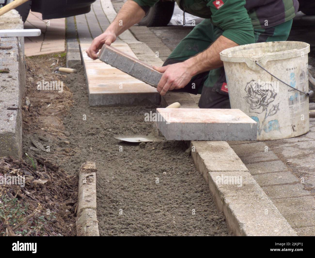 A man laying paving slabs on cement sand Stock Photo - Alamy