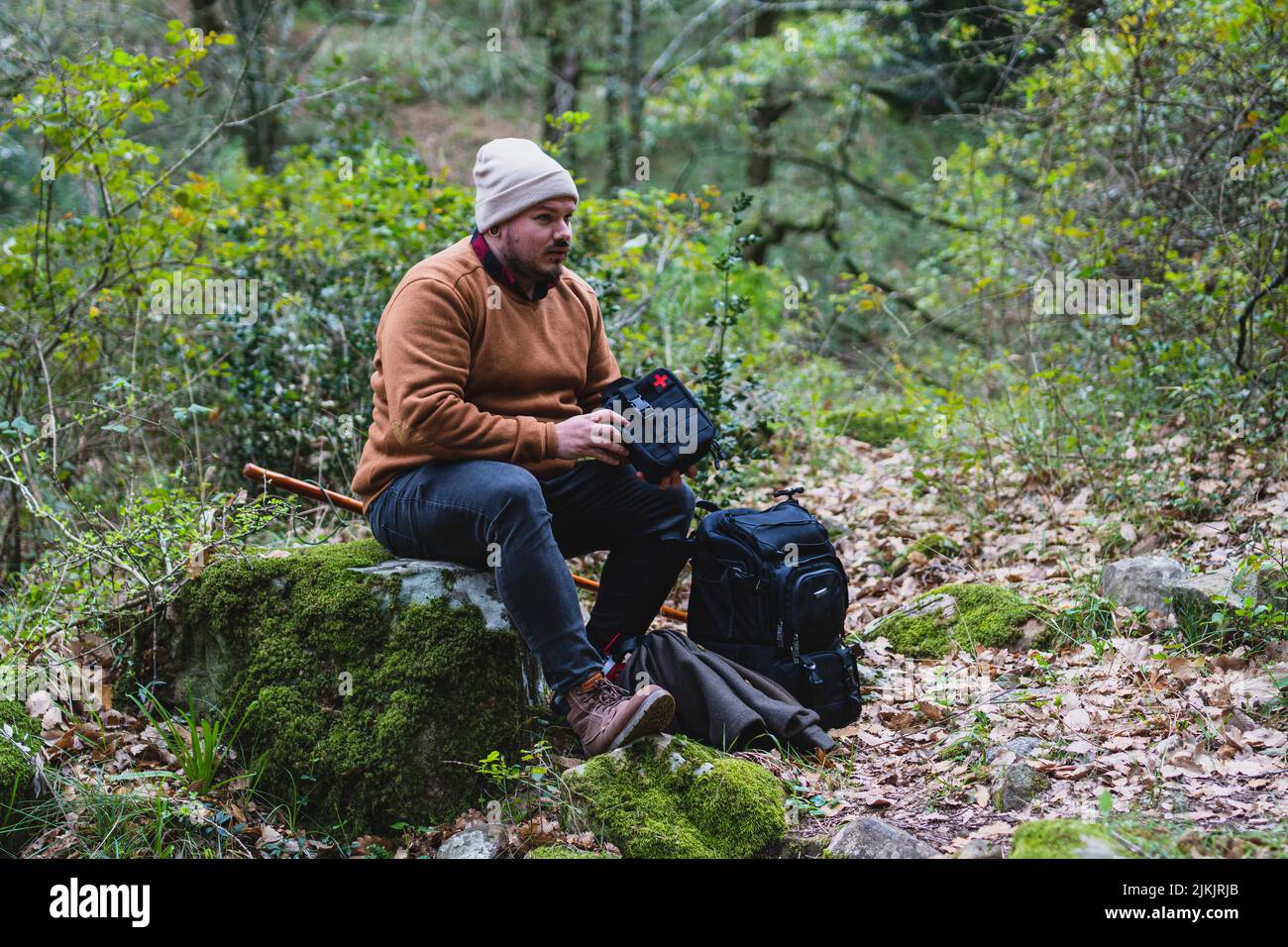 A caucasian man with professional photography equipment sitting on a trunk in the forest Stock Photo