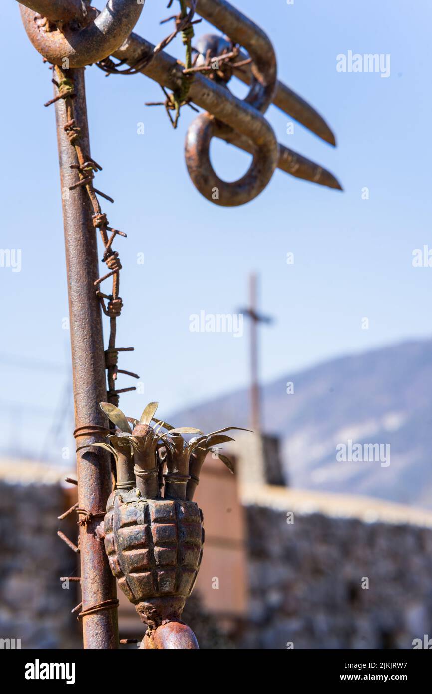 A vertical closeup of the metal pole with barbed wire and an old grenade. World War 1, north Italy. Stock Photo