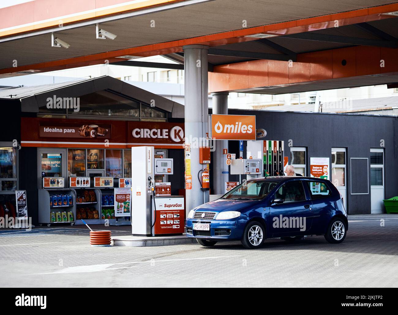A closeup of a blue tanking car by a pump of a Circle K gas station