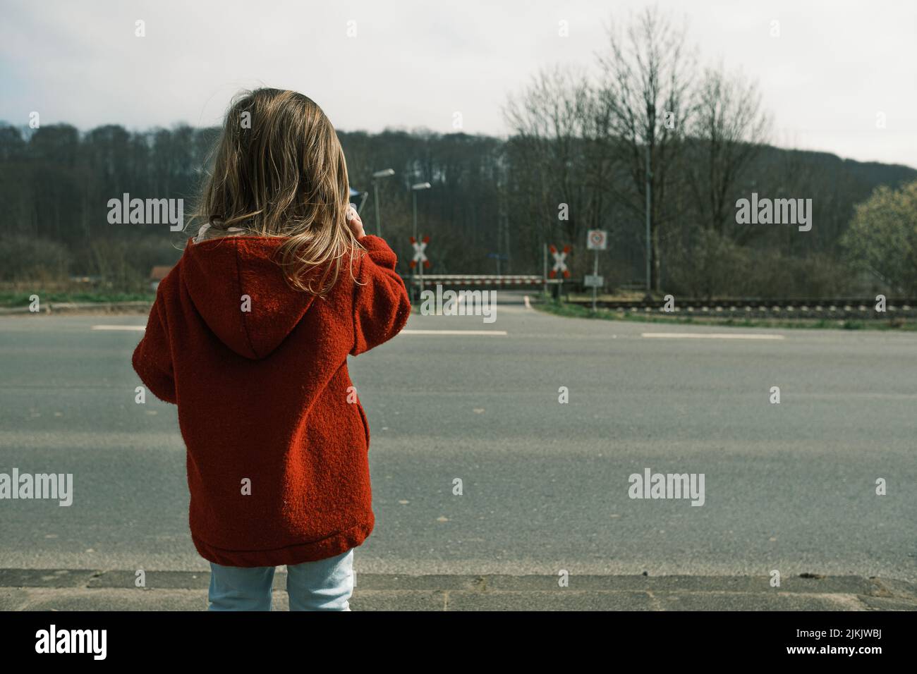A rear view of a female kid standing beside the road Stock Photo - Alamy