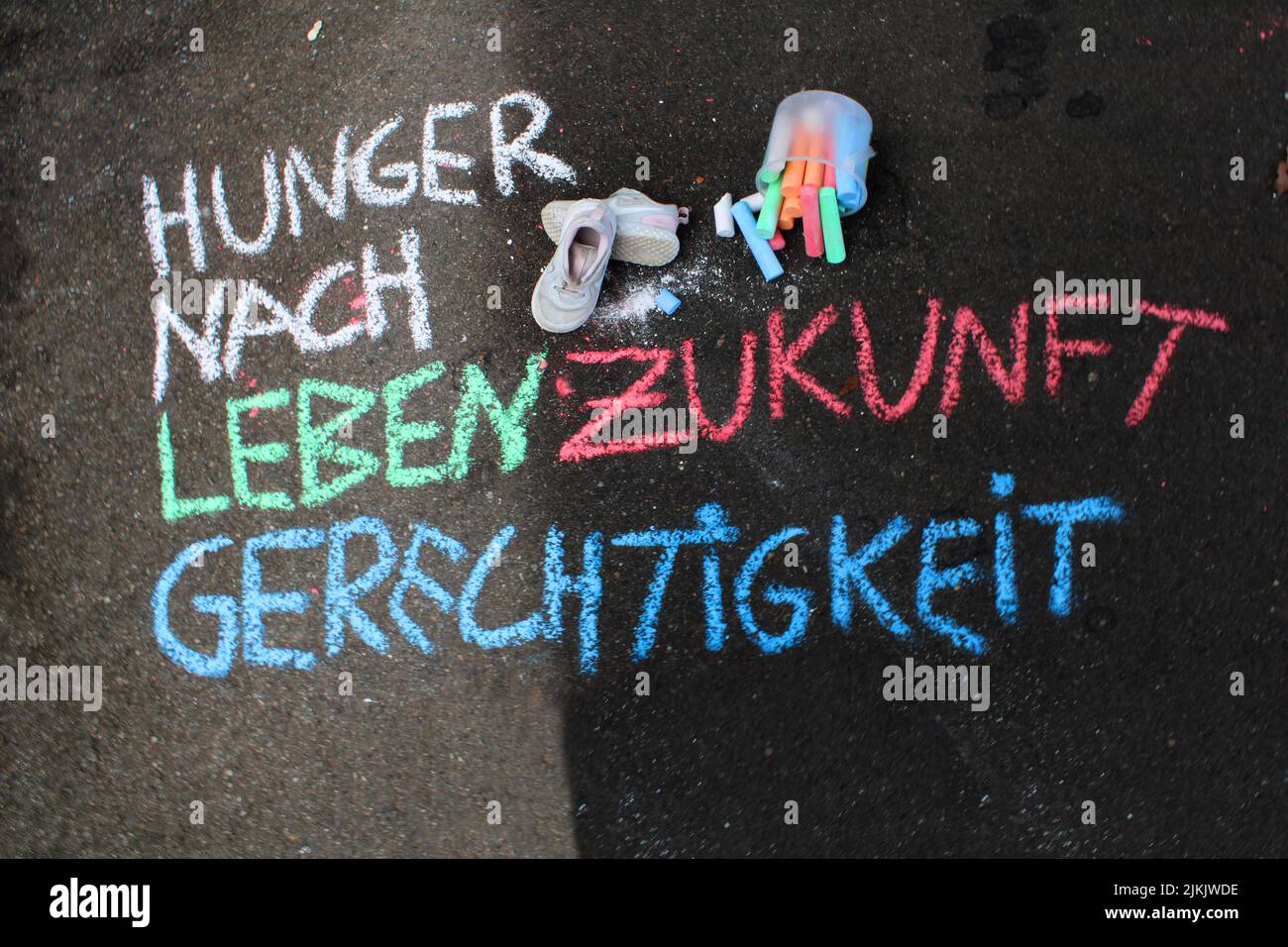 A colorful German text on the asphalt - Hunger for life, future and justice Stock Photo