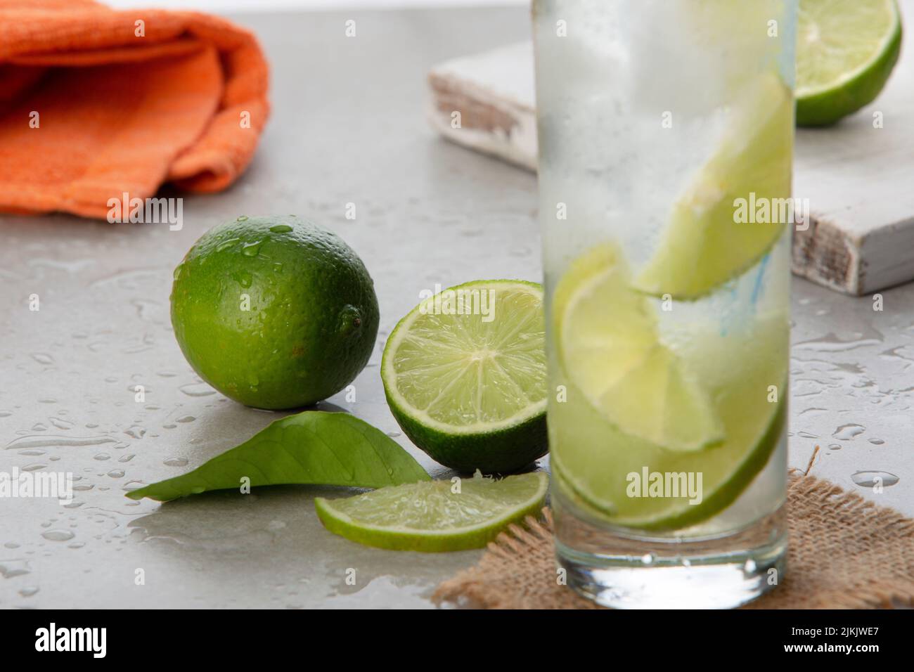 A selective focus shot of limes next to lemonade in a tall glass Stock Photo