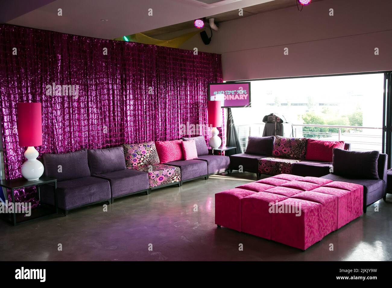 A decorative indoor media party event with pink purple decorations and furniture Stock Photo