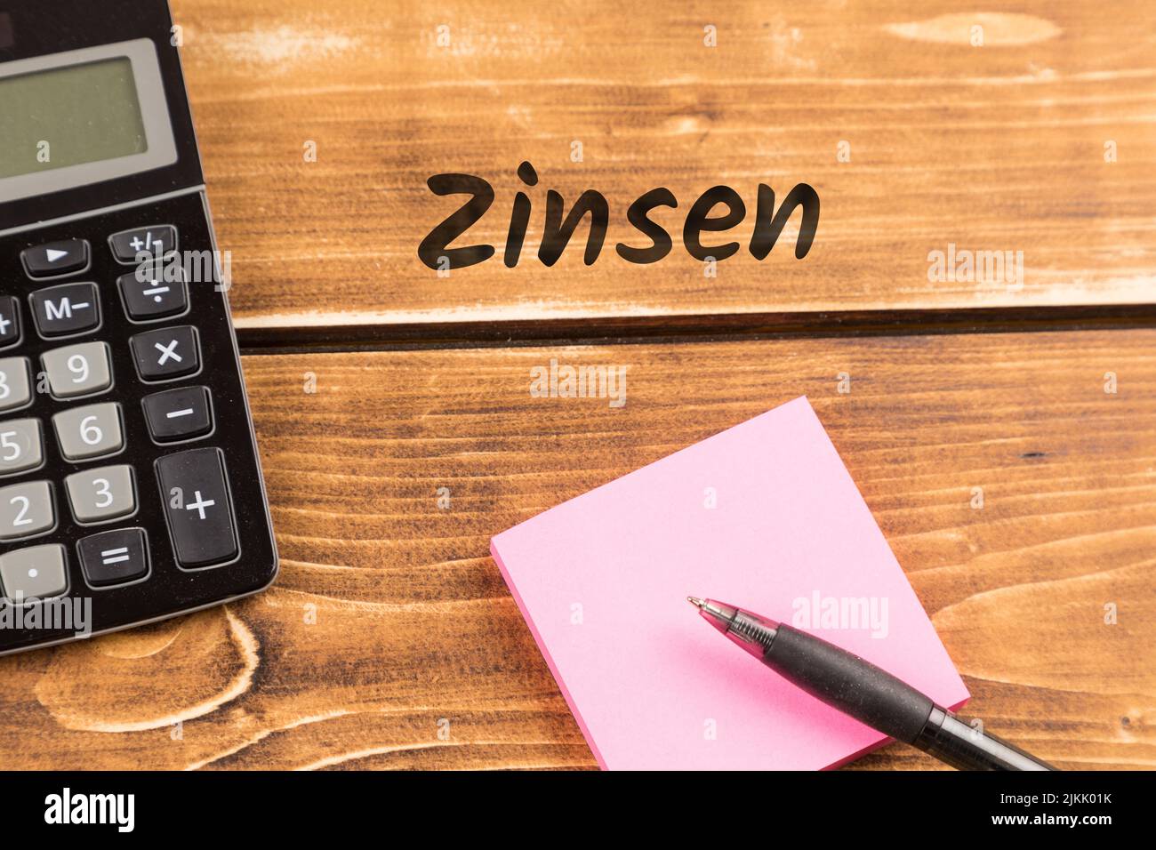 business desk with paper, pen and calculator with german text Zinsen, in english interest Stock Photo
