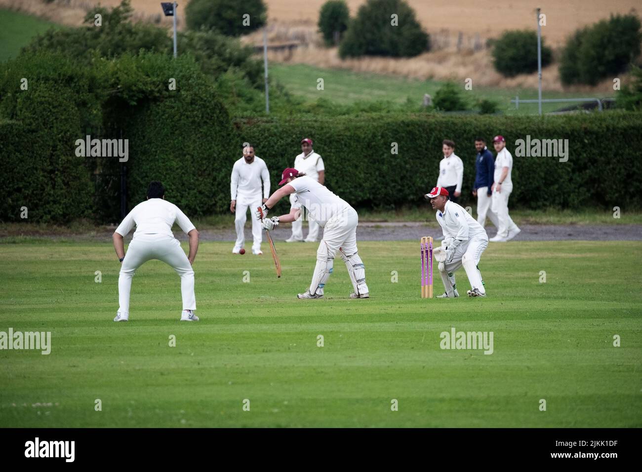 Cricket Batsman, Wicket keeper, fielders and spectators at a local village cricket match in Kirkheaton, Huddersfield, Yorkshire, U.K. Stock Photo