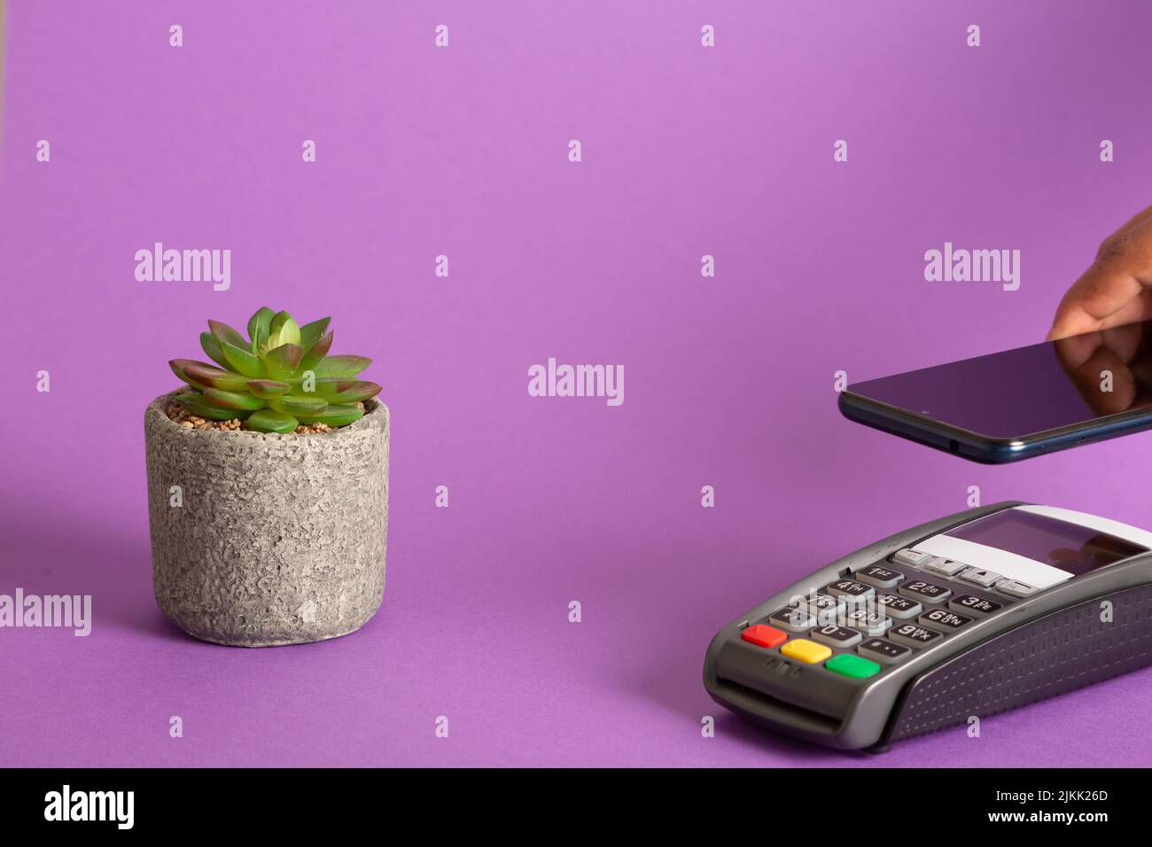A closeup shot of the POS terminal credit card machine and plant on a pink background Stock Photo