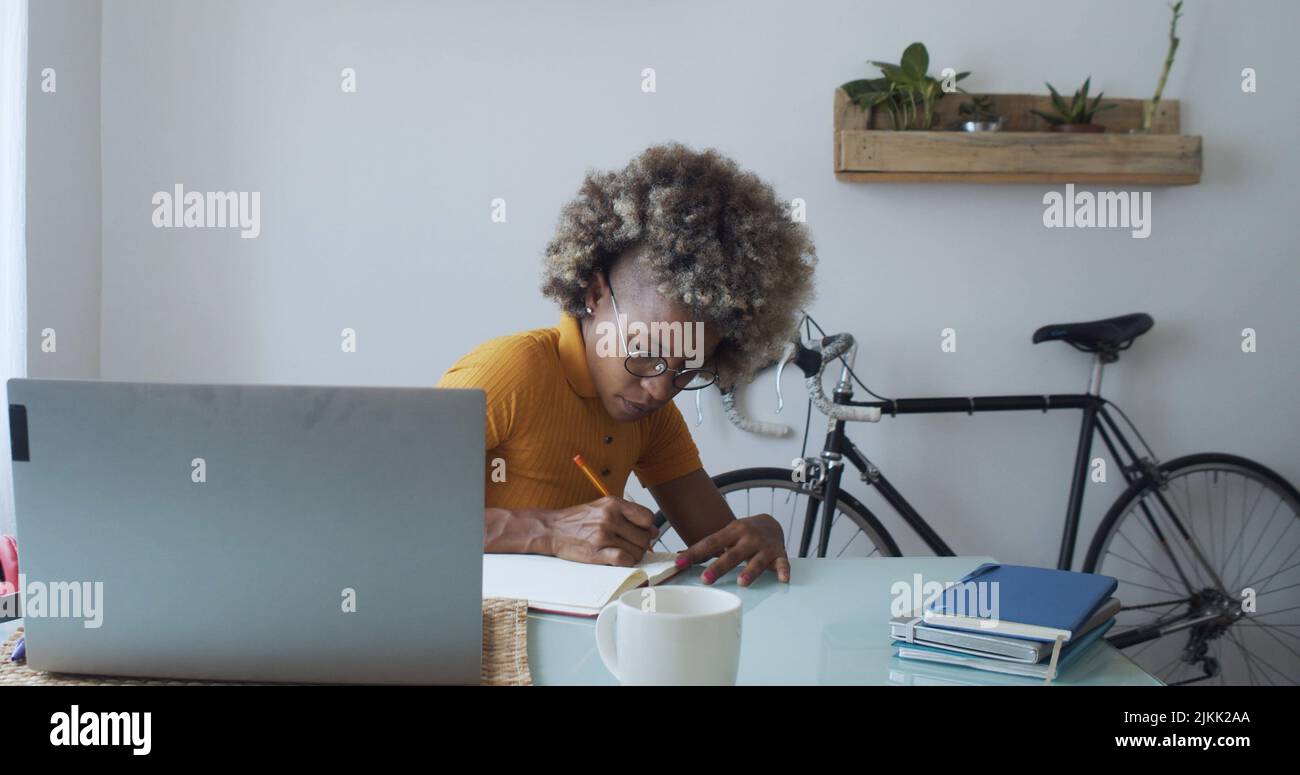 An African curly lady working in the office in front of a laptop Stock Photo