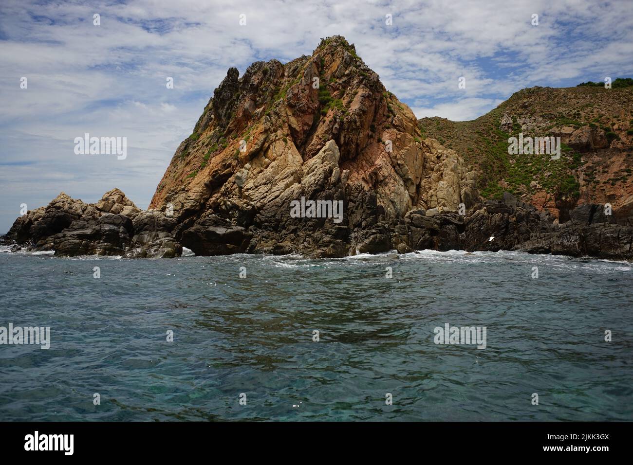 A beautiful shot of a Rocky mountain in the Sea under cloudy sky Stock ...